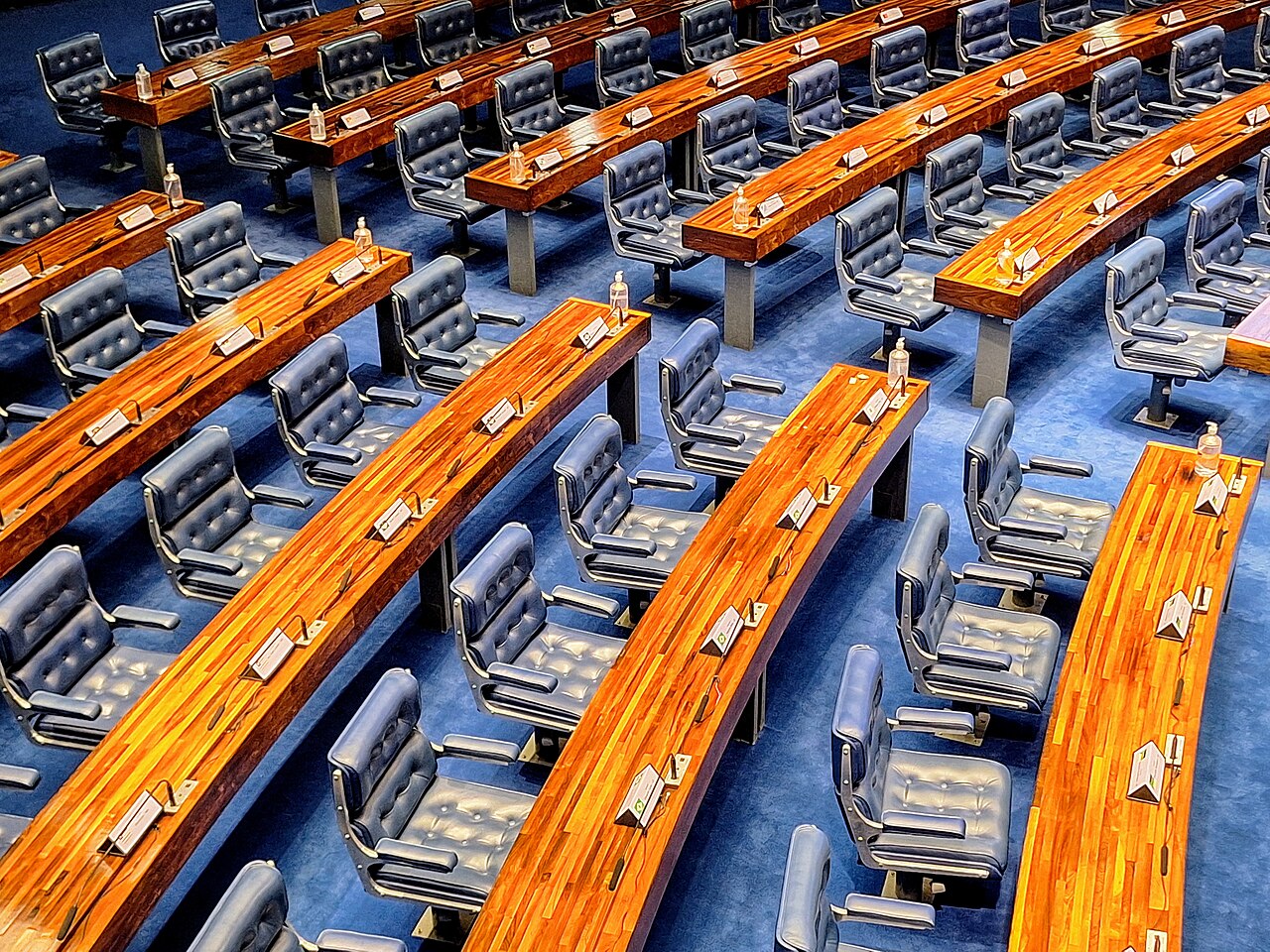 Bancadas de madeira e poltronas azuis vazias no Plenário do Senado Federal, vistas de cima